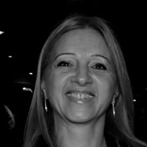 20260814-Graciela-Ciccia Smiling woman with long light hair wearing hoop earrings, photographed at night.