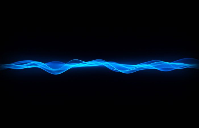 Abstract blue sine-wave ribbons flow across a black background, suggesting sound or energy waves.