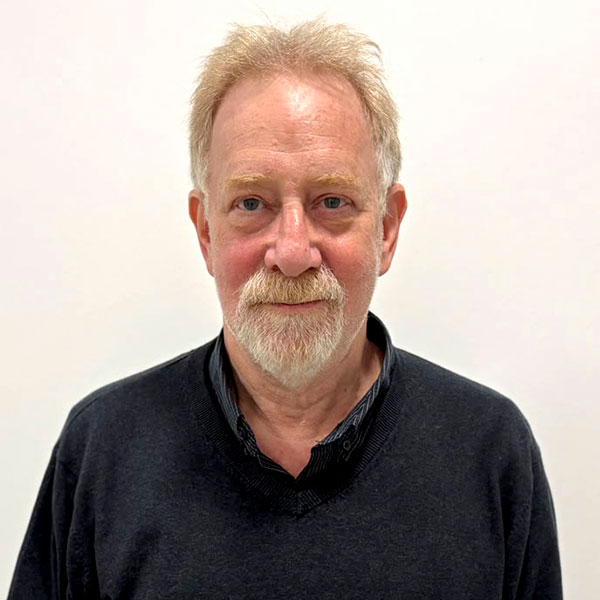 Head-and-shoulders portrait of a middle-aged man with blond hair and a white beard, wearing a dark sweater, against a white background.