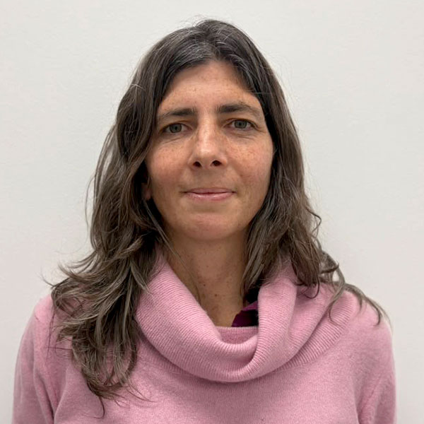 Portrait of a woman with shoulder-length brown hair wearing a pink cowl-neck sweater, facing the camera with a neutral expression.