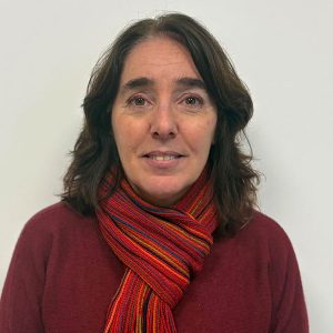 Portrait of a woman with shoulder-length dark hair, wearing a red striped scarf and maroon sweater, looking at the camera with a neutral expression against a light background.