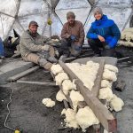 Three construction workers inside a geodesic dome sitting among foam insulation and scattered tools