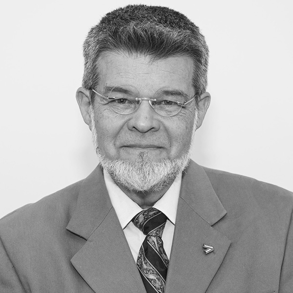 Professional head-and-shoulders portrait of a mature man with glasses and a gray beard, wearing a suit and tie.