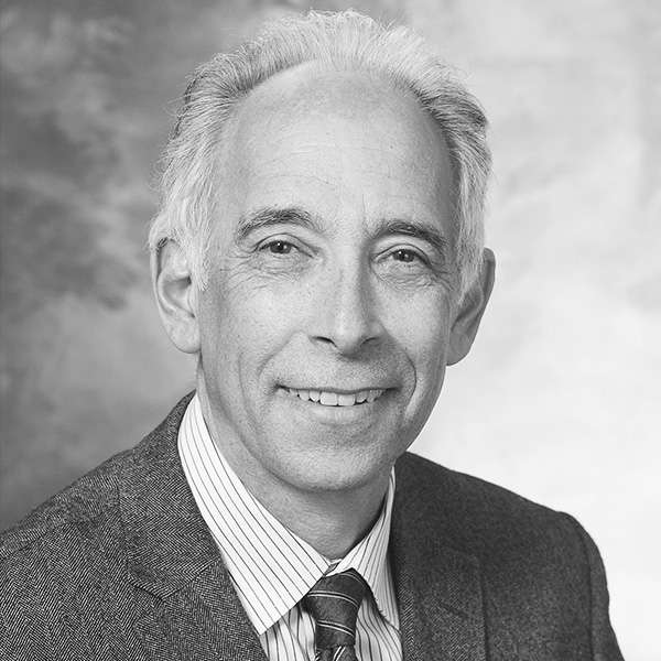Black-and-white head-and-shoulders portrait of a smiling man in a suit, suitable for a professional bio.