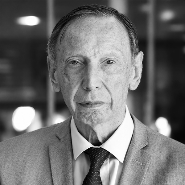 Professional head-and-shoulders portrait of an older man in a gray suit and tie, with a neutral expression for a business profile photo