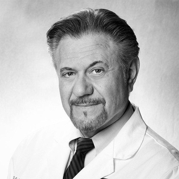 Portrait of a middle-aged male doctor in a white coat and striped tie, looking at the camera.