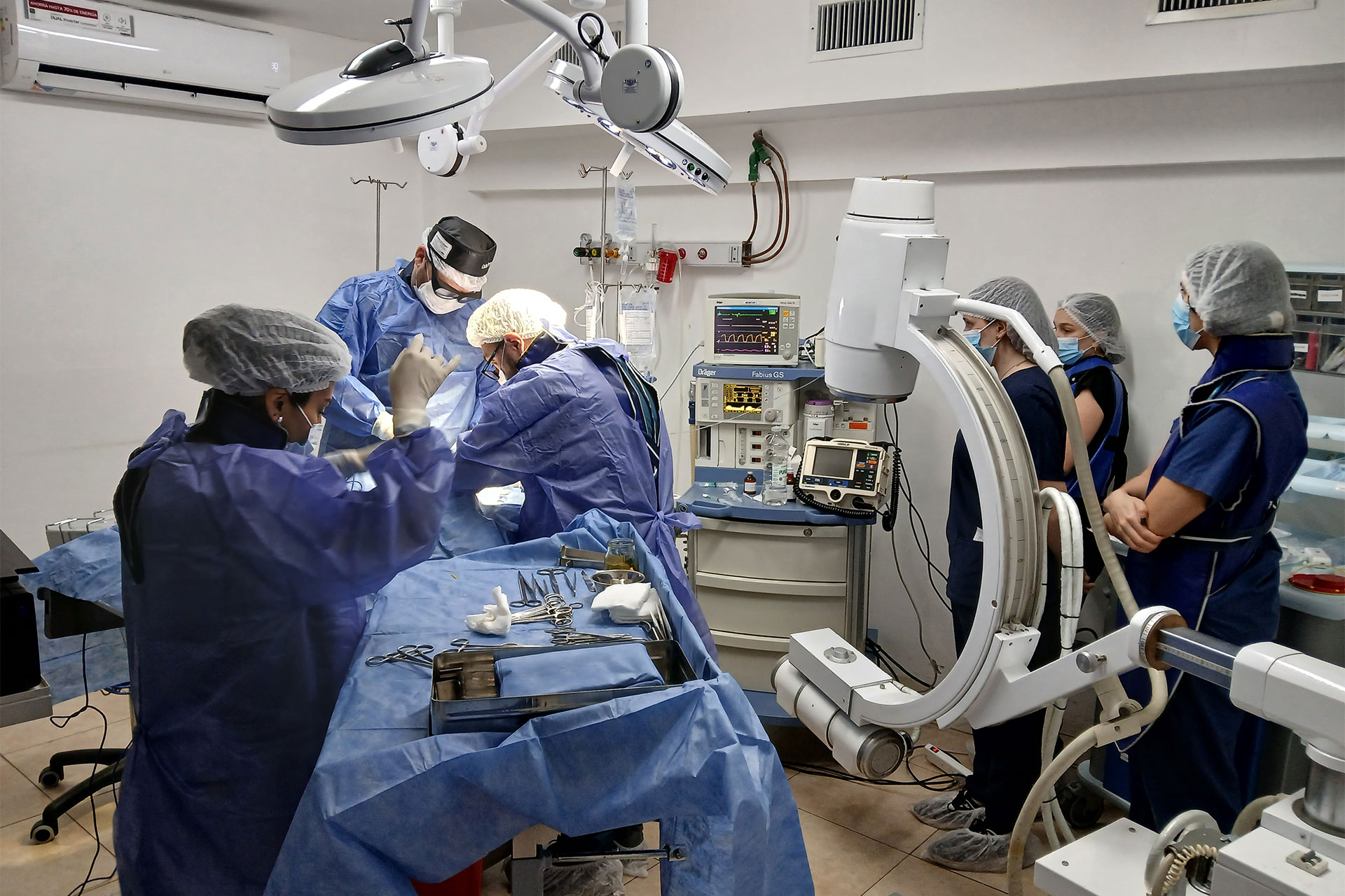 Surgical team in an operating room performing a procedure with monitors and equipment nearby